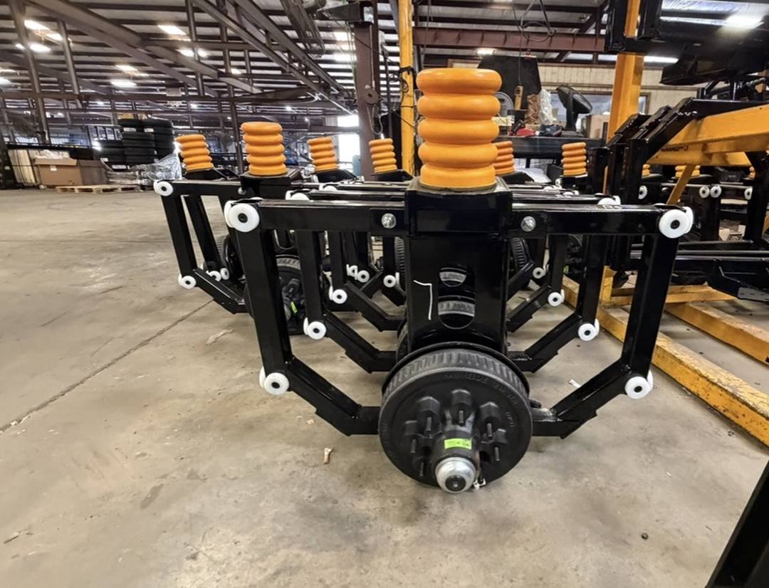 Torsion slide axle assemblies before installation, showing the slide blocks and the spring mounted above them