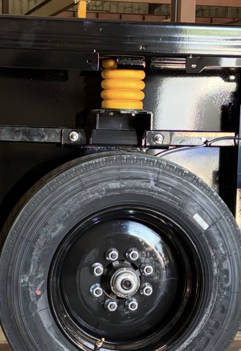 A single wheel installed on the chassis with the spring and slide bracket visible above it